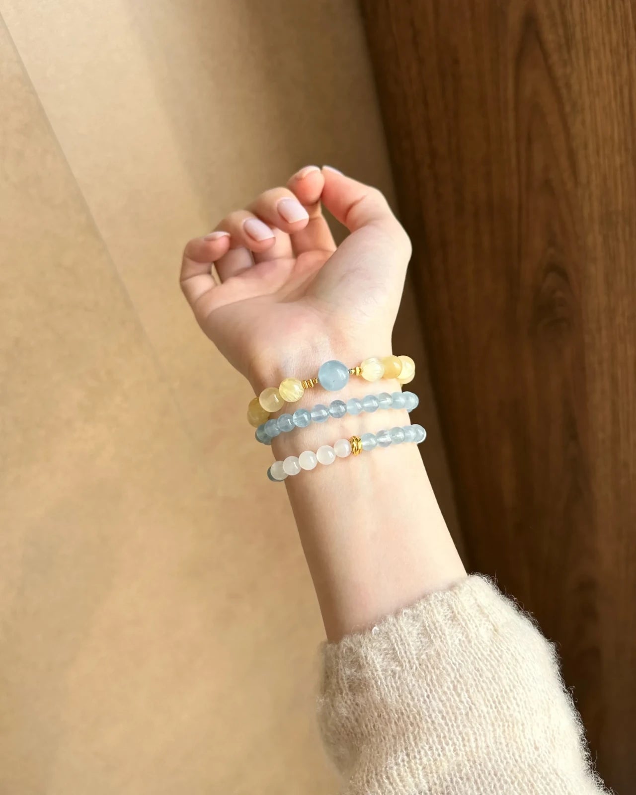 Close-up in soft sunlight—aquamarine and white moonstone 6mm bracelet with gold-plated S925 spacers, stacked with matching strands.