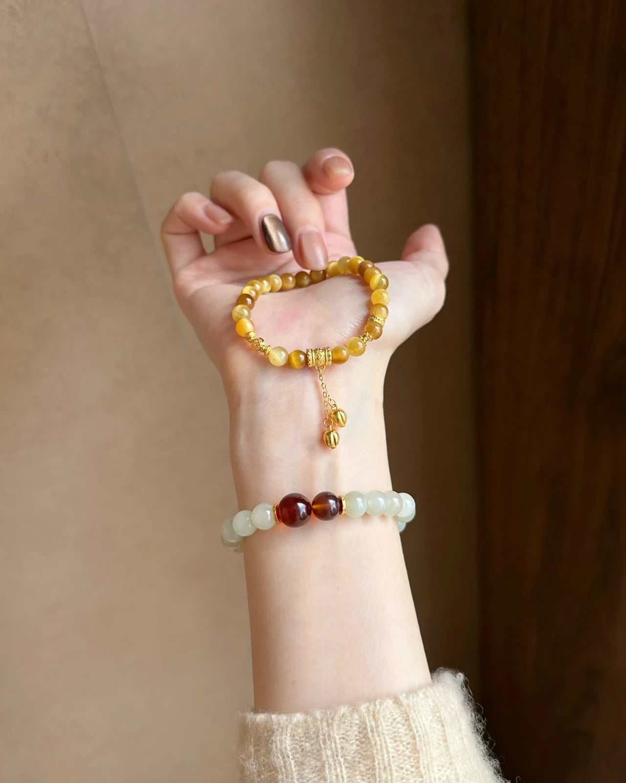 Handheld close-up of a 6mm golden tiger’s eye bracelet featuring gold-plated S925 accents and a twin-bead dangling charm chain; women’s beaded bracelet.