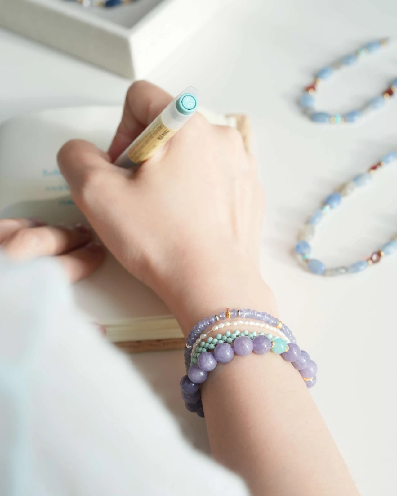 Top view of Purple Chalcedony & Amazonite bracelet on wrist at a desk