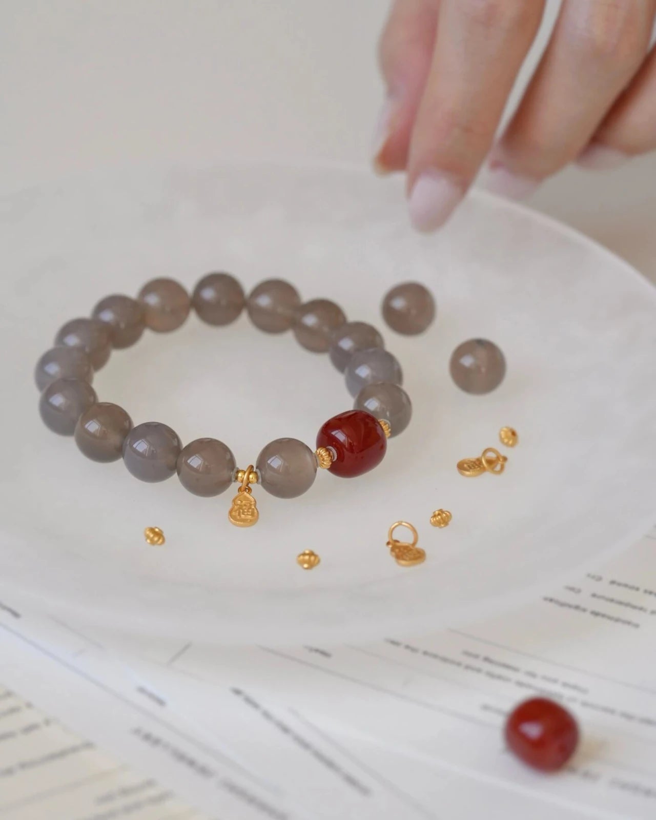 Balanced Energy Bracelet with Red Agate centerpiece and Gray Agate beads, displayed with gold-plated accents