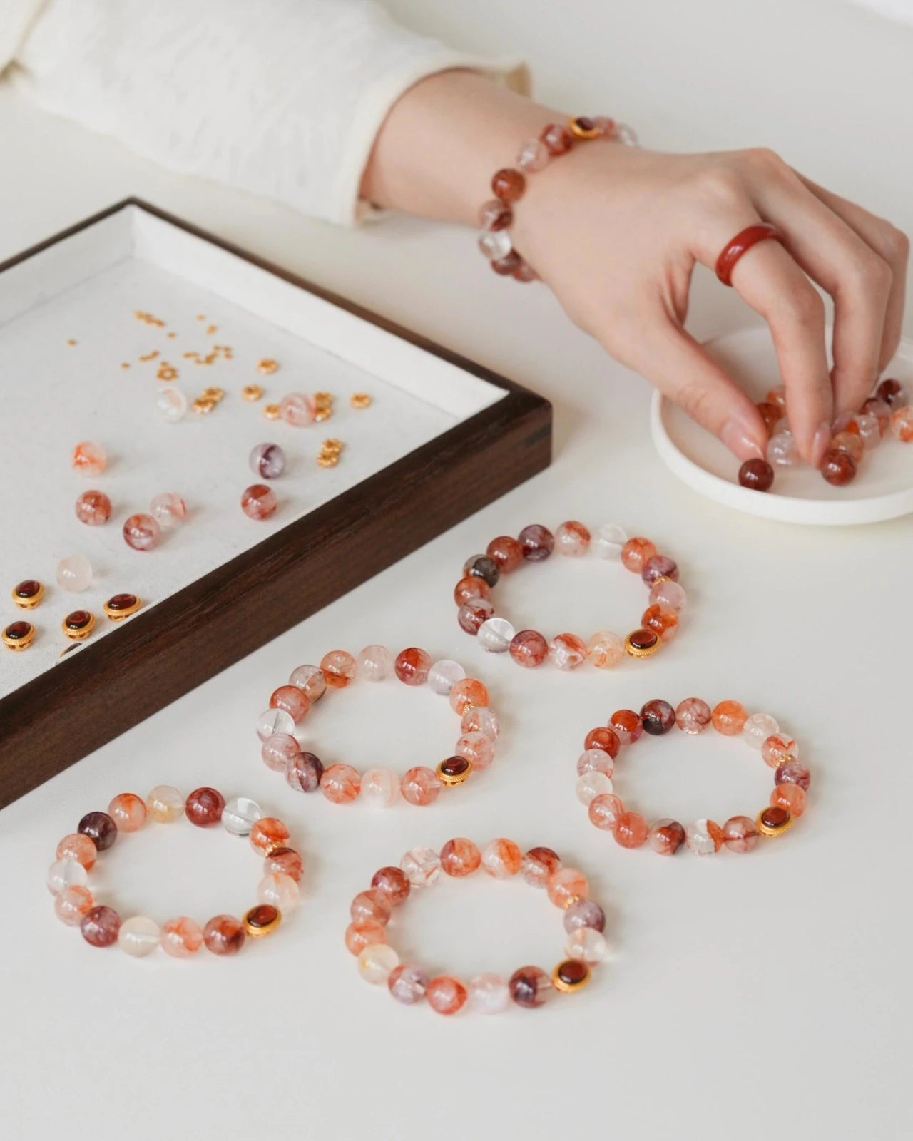 Flat lay of hematoid quartz bracelets—unique iron inclusions, garnet cabochon charm, subtle gold accents