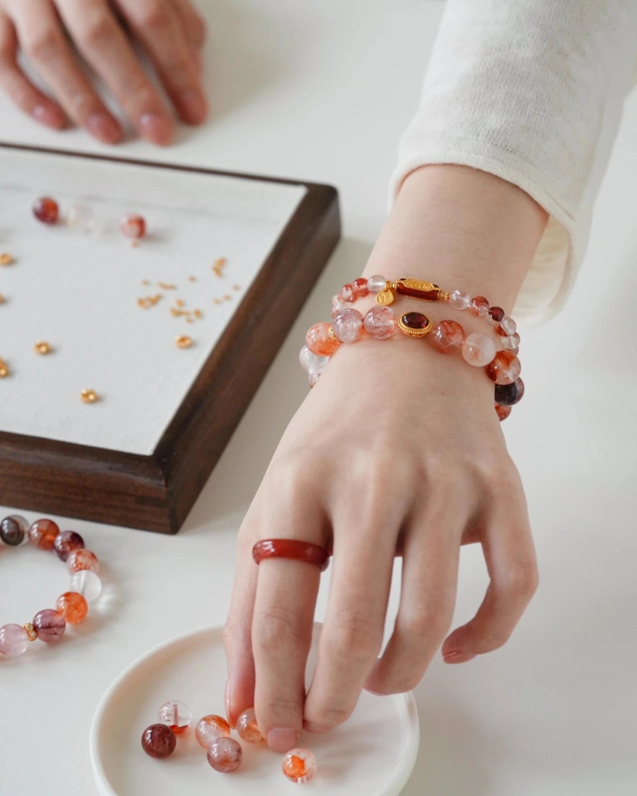 Lifestyle shot—hematoid quartz bracelet stack; garnet charm catching light while selecting matching beads