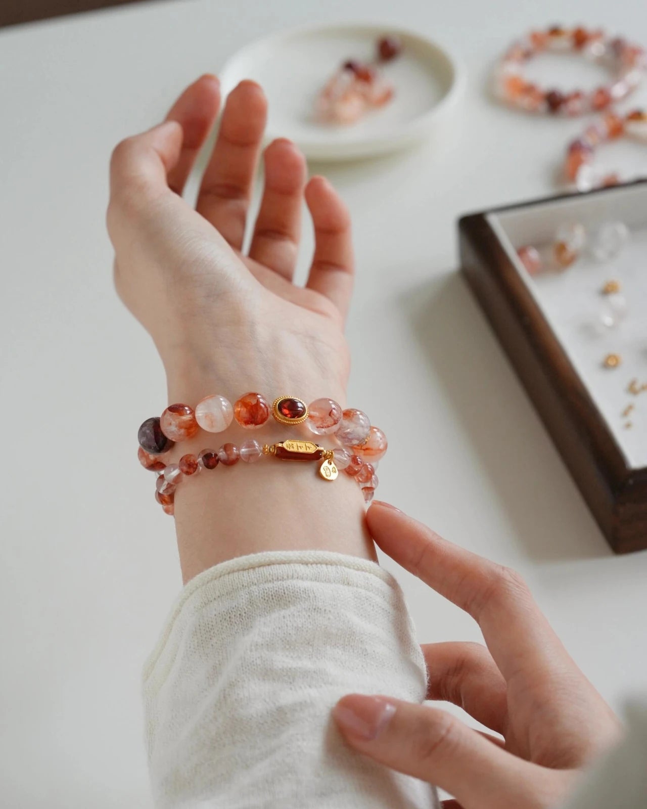 Stacked hematoid quartz bracelets on wrist with bezel-set garnet and gold accents; stackable beaded bracelet