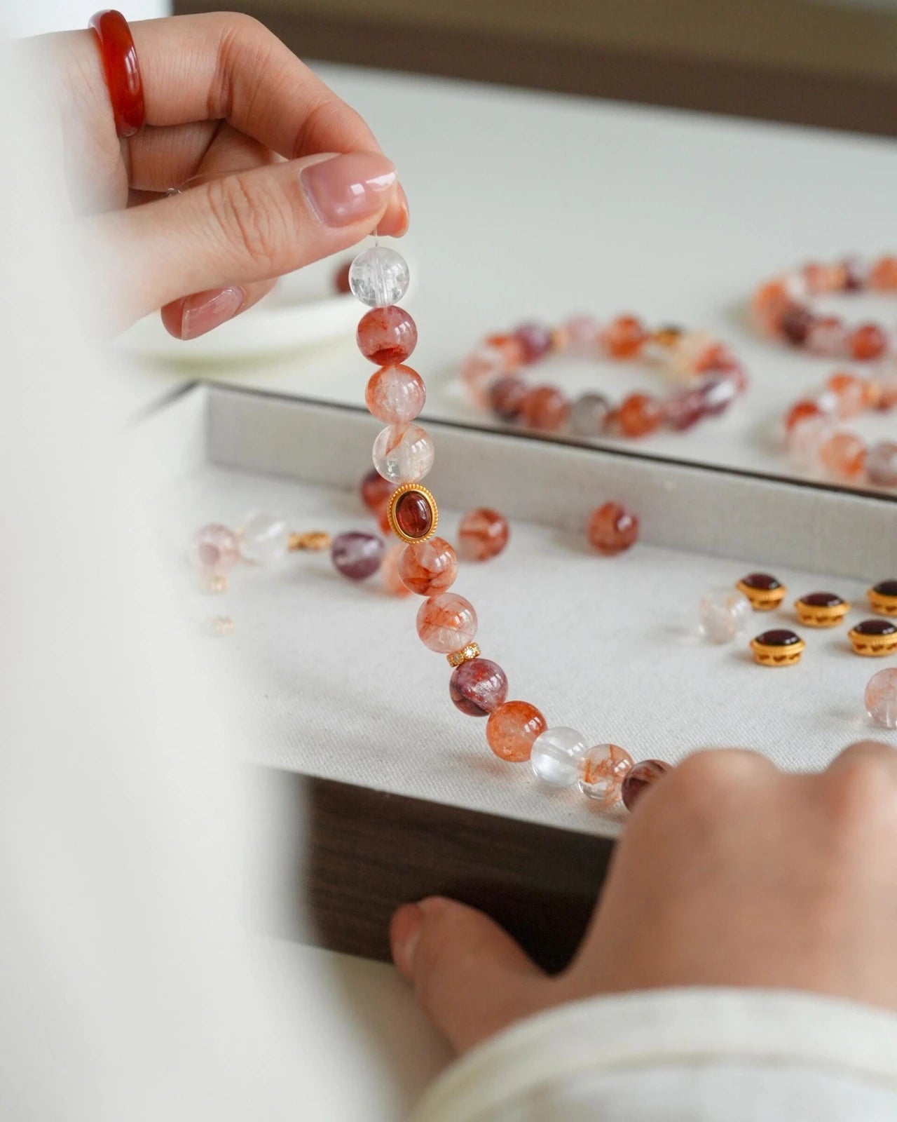 Stringing hematoid quartz beads with a small bezel garnet charm; elastic cord detail