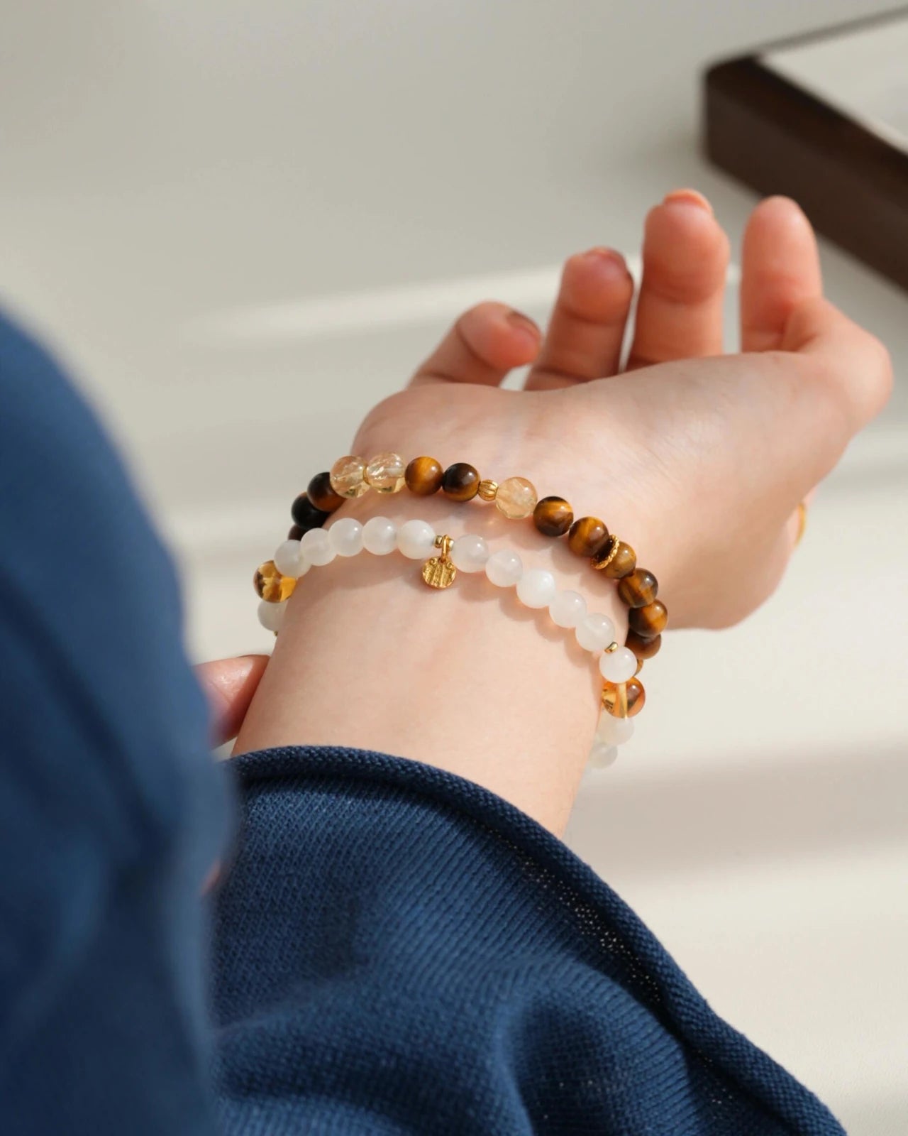 Lifestyle wrist stack—white moonstone and citrine bracelet layered with tiger’s eye; gold-plated S925 charm catching soft sunlight.
