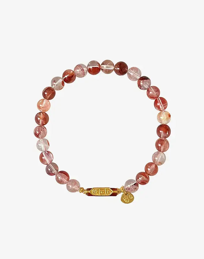 Flat lay of the Fierce Ground bracelet with hematoid quartz and red agate beads and a gold-plated silver barrel accent.