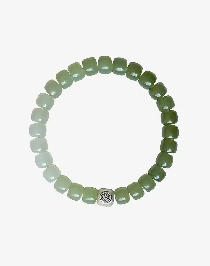Flat lay: Jade Harmony bracelet of gradient square nephrite-jade beads with a sterling-silver cube charm on gray background.