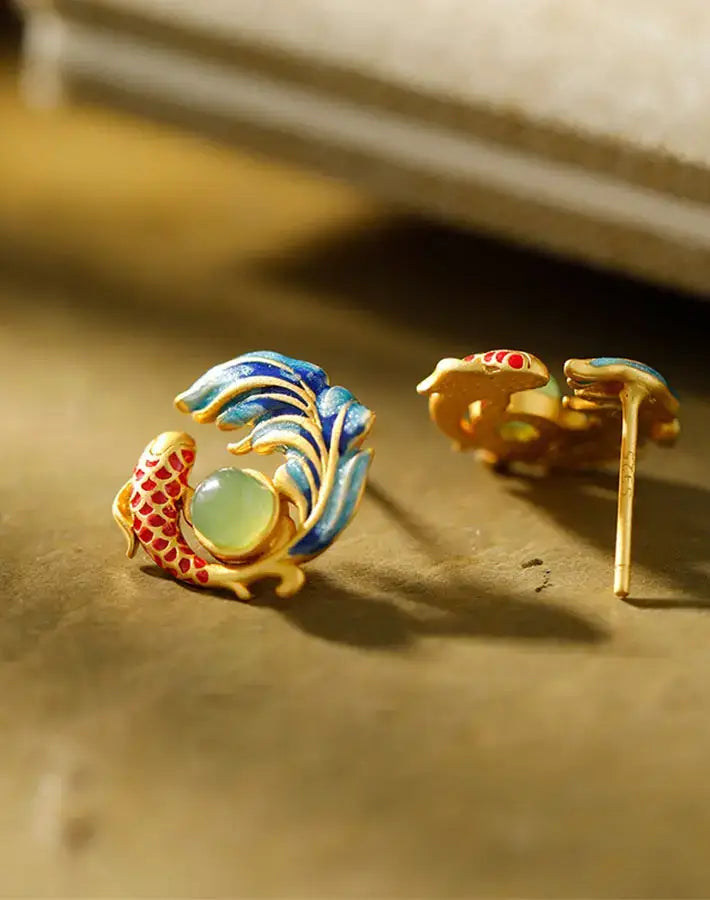 Styled shot of Koi Grace earrings on a warm surface, highlighting nephrite jade, enamel koi details and gold-plated S925 silver.