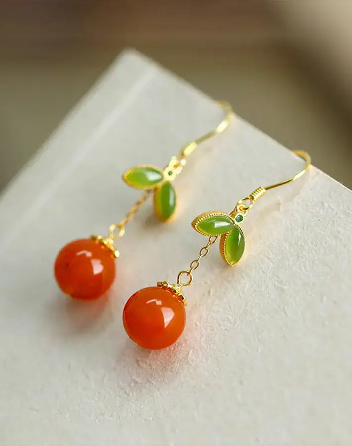 Close-up of Radiant Ember earrings highlighting red agate spheres, nephrite leaves and gold-plated S925 silver chain links.