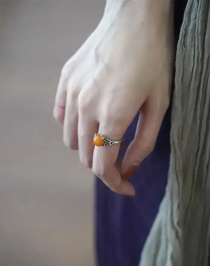 Side view of relaxed hand wearing the Solar Calm amber ring with artisanal sterling-silver scroll band.