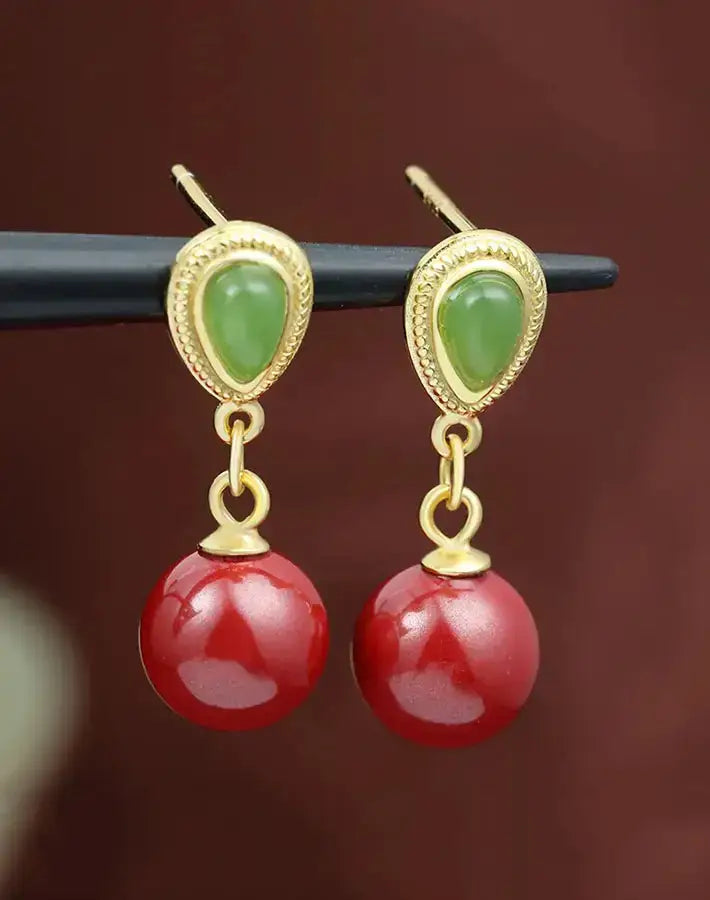 Vital Grace earrings featuring nephrite studs and cinnabar beads on gold-plated S925 silver, suspended from a sleek black rod.